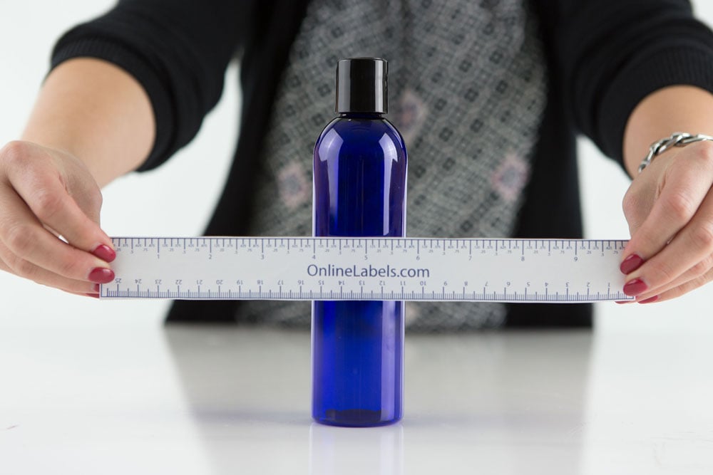 Holding printable, paper ruler over bottle for ways to measure curved containers