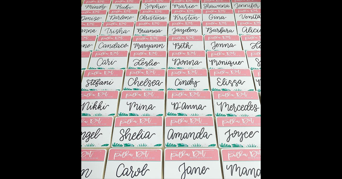 Name tag example, pulled from @taylorofalltrades: branded name tag stickers with pink headers, cursive names, and green floral accents